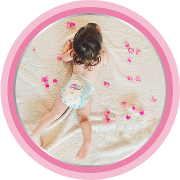 Newborn laying in bed with rose petals as soft as baby skin moisturizing cream.